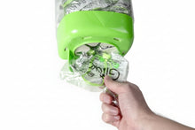Load image into Gallery viewer, Hand holding a green dispenser with clear bags filled with green and black items on a white background
